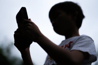 A-7-year-old-boy-looks-at-a-phone-screen